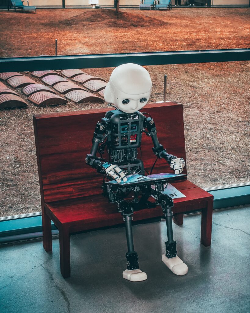 Robot sitting on bench and looking at a magazine or tablet